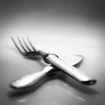 Two. knife and fork over glass with reflection and shadow Fotos Stock
