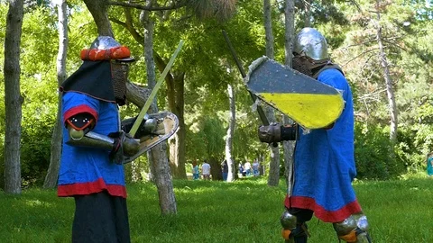 Two knights practice blows with a sword in a training session in the park Stock Footage 122079985