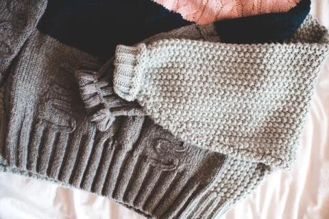 Two knitted sweaters folded in bed top view. Winter season concept. Stock Photos