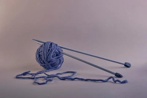 Two knitting needles in a ball of threads of a beautiful gray-blue color on a 스톡 사진