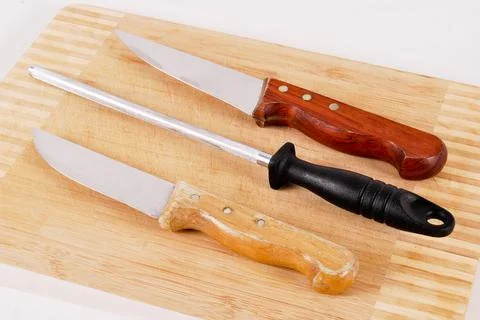 Two knives and sharpening tool on a bamboo cutting board Stock Photos