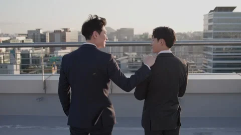 Two Korean Businessmen Talking on Rooftop with City View Stock-Footage 337451130