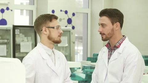 Two laboratory technicians share a light-hearted conversation in a modern lab Stock-Footage 311942444