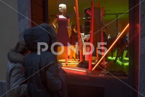 Two ladies observe a showcase in the historic center of Varese Stock Photos