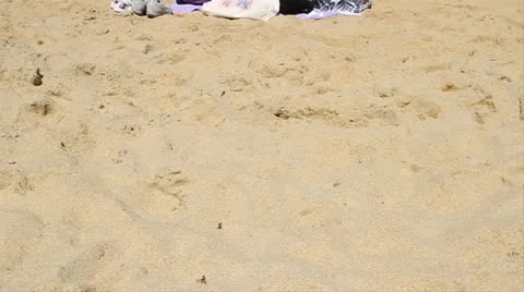 Two ladies sit on sandy beach Stock Footage 21545493