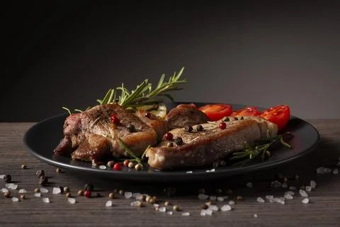 Two lamb chops rest on a dark gray plate Stock Photos