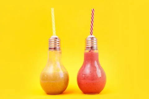 Two lamp- shaped jars with fruit smoothies isolated on yellow background. Stock Photos