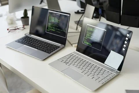 Two laptop computers with coded data and notepapers on screens Stock Photos