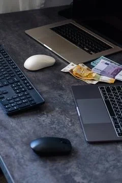 Two laptops are positioned on a dark desk alongside keyboards and a computer  写真素材