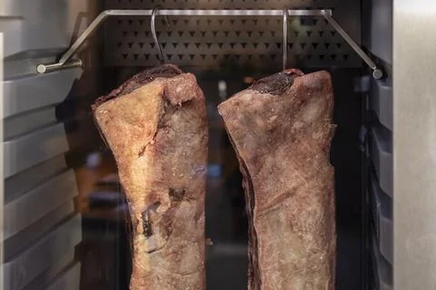 Two large beef cuts hang inside a dry aging fridge, showcasing the unique p.. Stock Photos