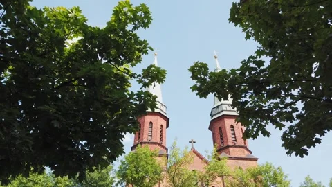 Two large brick churches standing among trees under blue sky outdoors Video stock 342135035