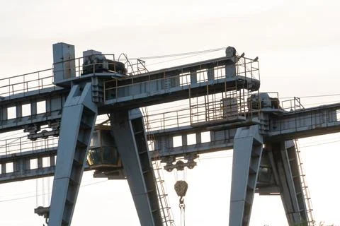 Two large bridge cranes on the background of the sky at sunset. Outline of a  Stock Photos