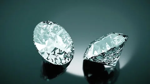 Two large brilliant cut diamonds slowly rotate on a reflective surface, creating Stock Footage 306231819