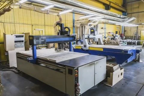Two large cnc machine cuts blanks of various shapes on a plywood sheet Stock Photos