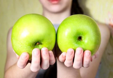 Two large green apples in a woman's hands. Blurry. Stock Photos