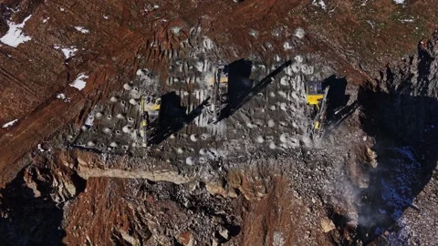 Two large machines operate on a rocky terrain at a mining site Stock Footage 337940320