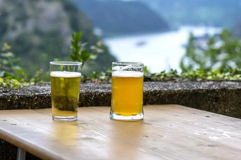 Two large mug of beer standing on a wooden table in the background a blurry r Stock Photos