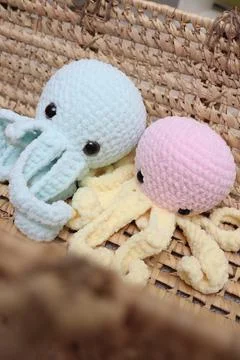 Two large octopuses sit in a straw basket. Close-up of large knitted toys. pink Stock Photos