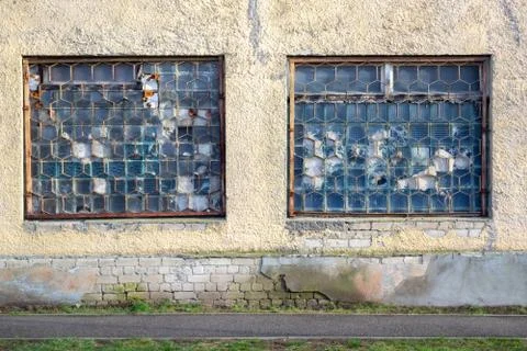 Two large old windows of an abandoned factory. Lattice on the broken windows. Stock Photos