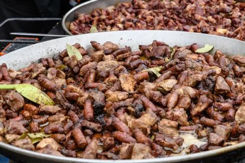 Two large pans with different types of deep fried meat pieces at a food market Stock Photos