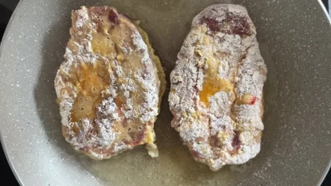 Two large pieces of battered meat are fried in boiling vegetable oil in a pan Stock Footage 244873870