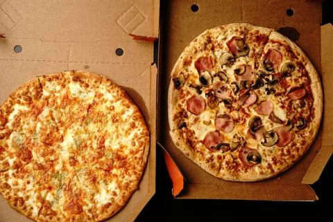 Two large pizzas in open boxes on a black background. Top view. Foto stock
