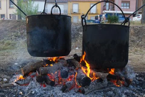 Two large pots or copper pots hanging on the fire with oak firewood for cooking Stock Photos