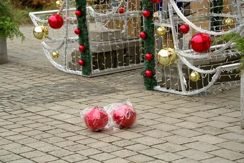 Two large red Christmas tree balls in plastic packaging lying on the paving.. Stock Photos