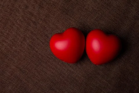 Two large red hearts on a textile background close up Stock Photos