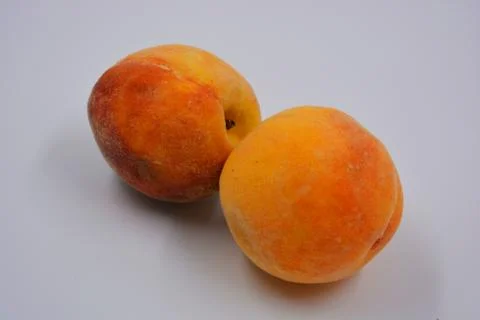 Two large ripe red-orange delicious peaches located on white plate. Stock Photos