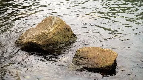 Two large rocks are floating in a body of water Stock Photos