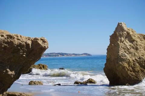 Two large rocks with ocean waves in the middle and gorgeous blue ocean and sky Foto stock