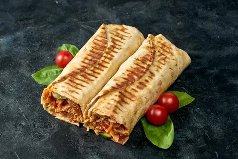 Two large shawarma roll with chicken and vegetables on a dark textured backgr Stock Photos