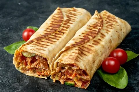Two large shawarma roll with chicken and vegetables on a dark textured backgr Stock Photos