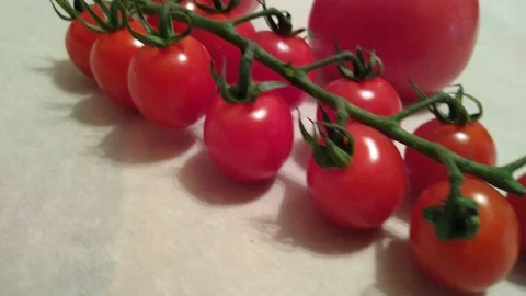 Two large tomatoes and cherry tomatoes on branches close up on a beige Stock Footage 144099297