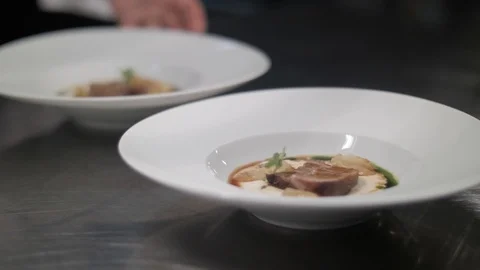 Two large white plates with serving dish on table. Chef hands rotate decorated Stock Footage 88674533