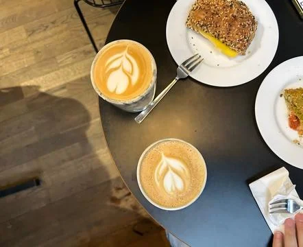 Two lattes and two slices of cake on a black table. Stock-Fotos