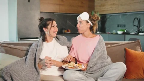 Two laughing girlfriends having fun in bedroom and eating sweet snacks during Stock-Footage 279028434