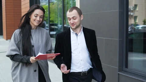 Two laughing smart colleagues walk on the city street and discussion about new c Stock Footage 199492071