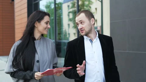 Two laughing smart colleagues walk on the city street and discussion about new c Video stock 199492163