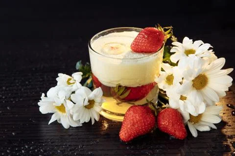 A two-layer strawberry cream dessert stands on a dark wooden table. Stock Photos