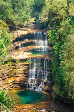 Two layered waterfall falling from mountain top in deep green forests at morn 스톡 사진