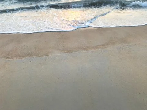 Two layers of brown sand beach with sea waves and sunset Stock Photos