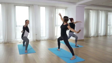 Two learners practicing yoga sequence with teacher guiding them Video stock 71988285