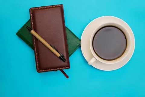 Two leather-bound notebooks lie against a blue background. There's a pen and  Stock Photos