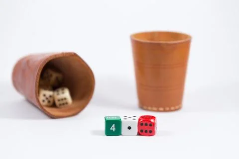 Two leather cups filled with dice and three colored dice isolated on white Stock Photos
