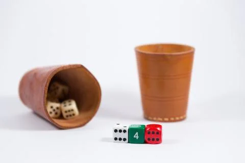 Two leather cups filled with dice and three colored dice isolated on white Stock Photos