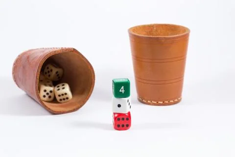 Two leather cups filled with dice and three colored dice isolated on white Stock Photos