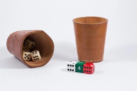 Two leather cups filled with dice and three colored dice isolated on white Stock Photos