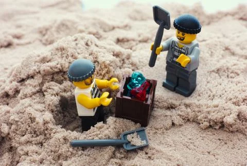Two Lego robbers digging out box of gems from sand Foto stock